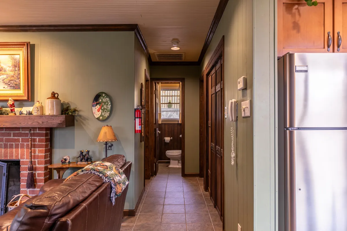 A cozy living area featuring a stone fireplace, plush sofa, and a view into the kitchen area. The space is warm and inviting, suggesting a comfortable retreat after a day outdoors.