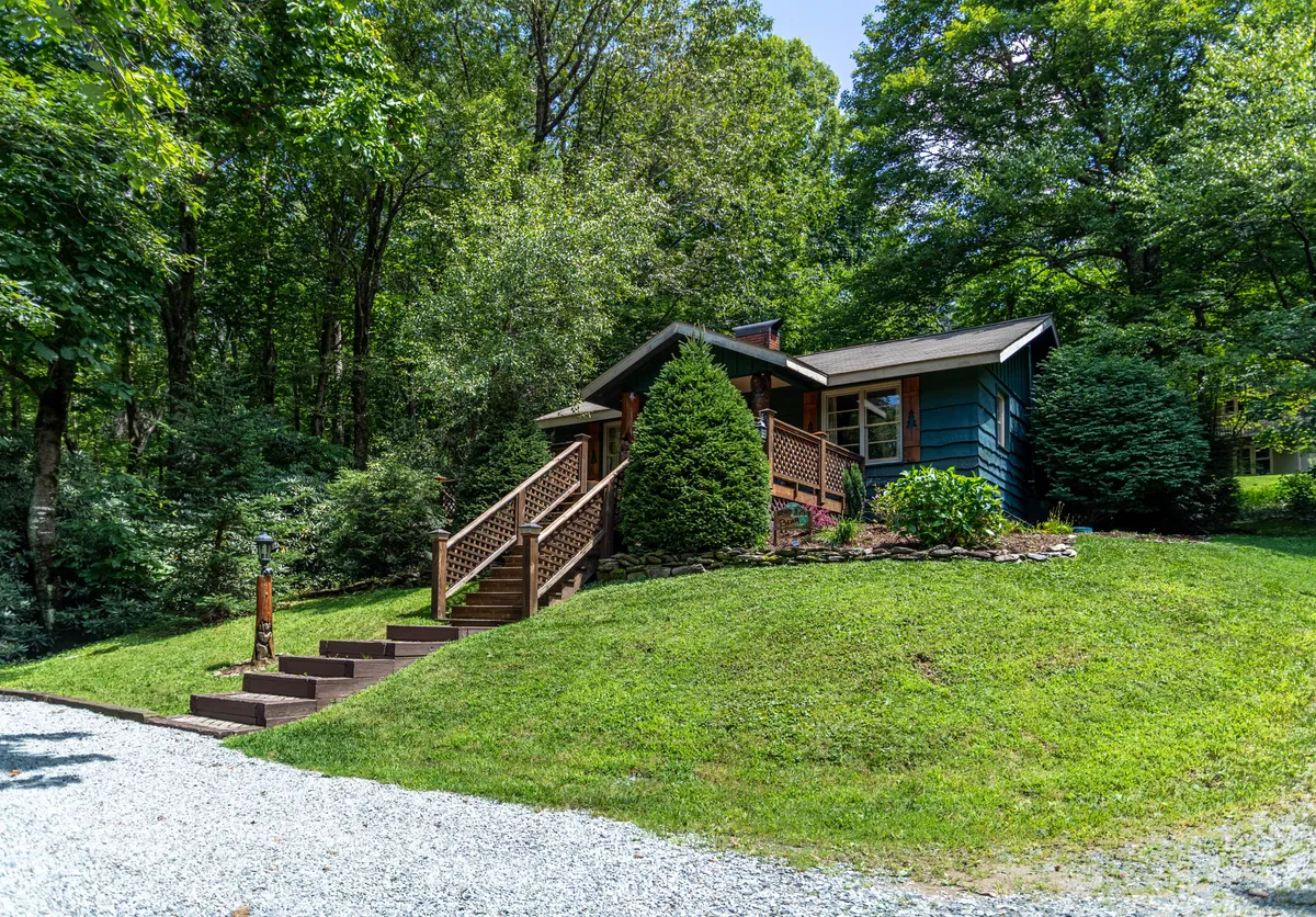 A wide exterior shot of the home displays the welcoming porch, landscaped yard, and surrounding trees. The scene evokes a sense of arrival and relaxation, setting the tone for a family retreat close to major attractions.
